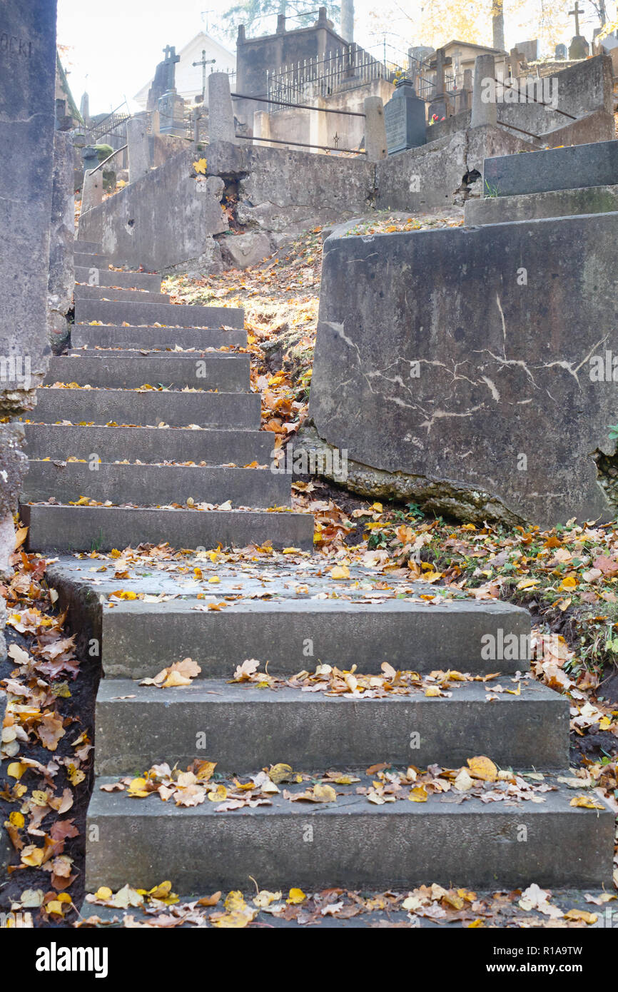 Dark scalinata di pietra con foglie sul cimitero, in salita. La stagione autunnale. Foto Stock