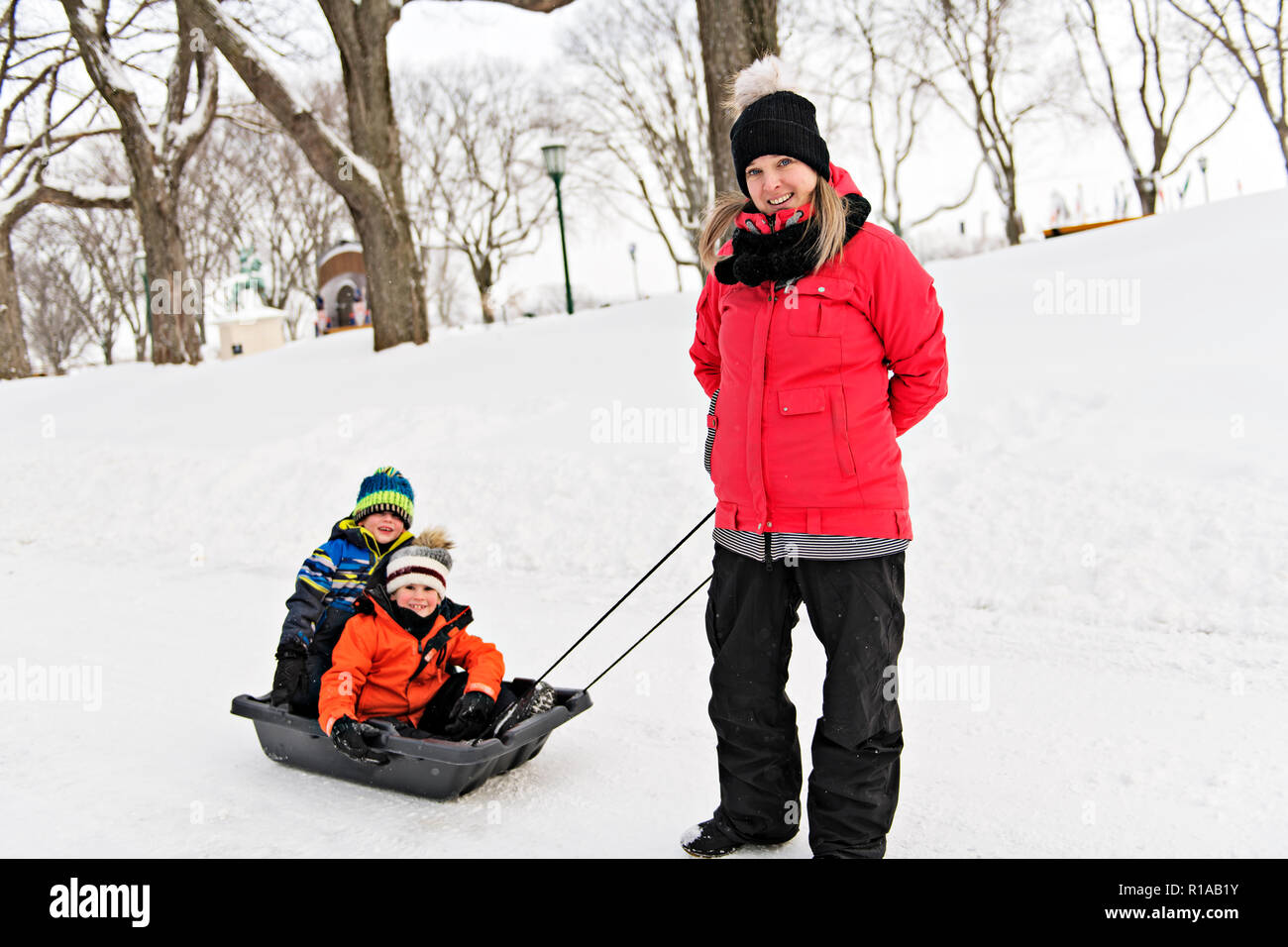 Madre trascinare i suoi due boy in sled Foto Stock