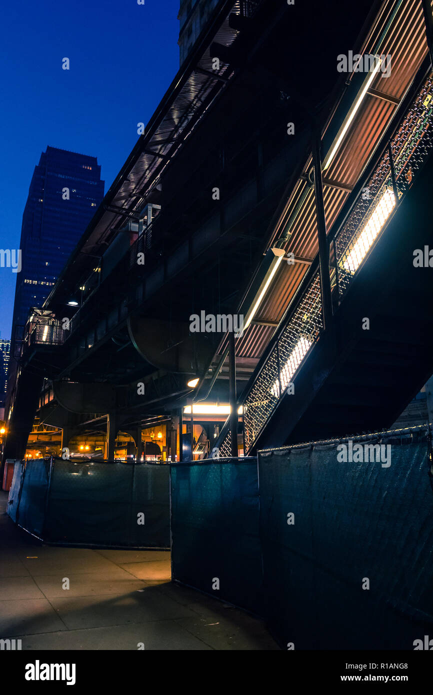 Vintage sopraelevata di Chicago CTA treno stazione della metropolitana in costruzione di notte con lo skyline e un grattacielo in background Foto Stock