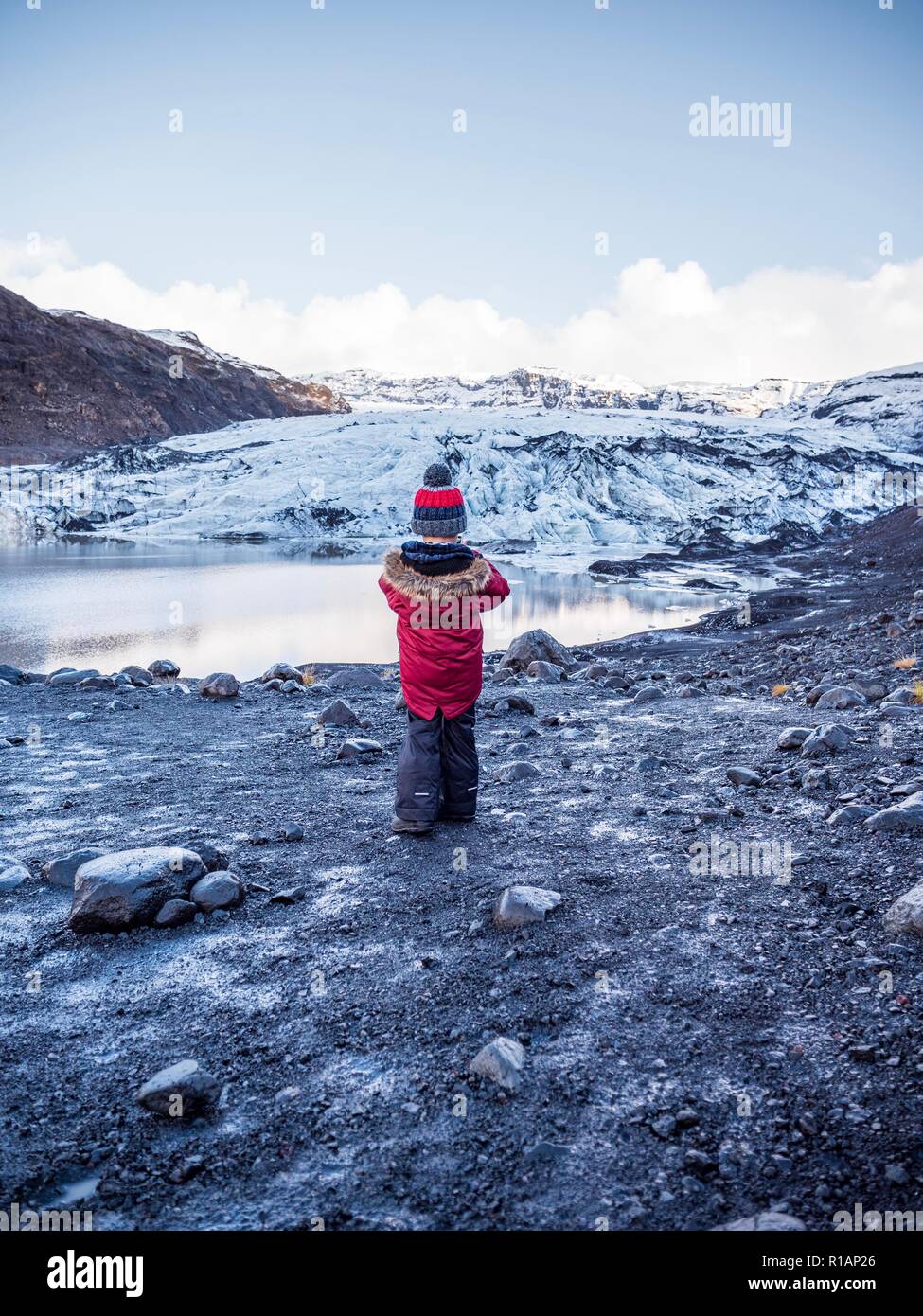 Un piccolo ragazzo stava fissando la bocca di un ghiacciaio nel sud dell'Islanda Foto Stock