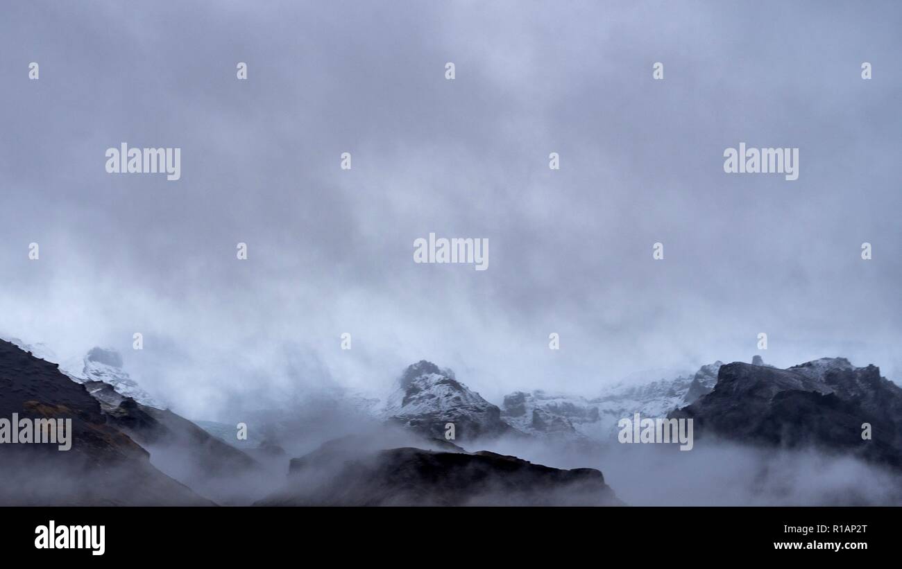 Le vette delle montagne che appare attraverso il cloud nel sud dell'Islanda Foto Stock