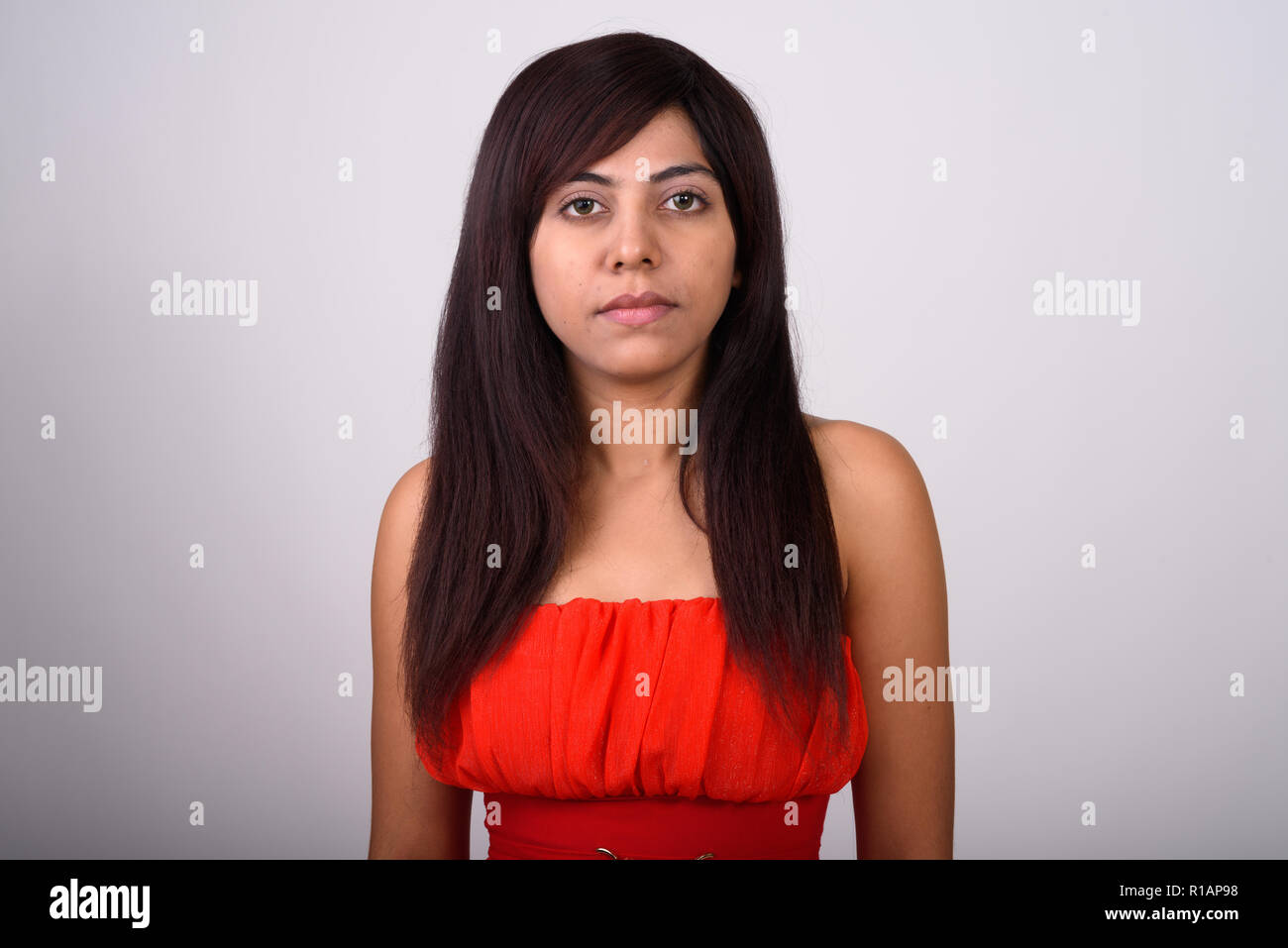 Close up di Persiano giovane donna che indossa abito rosso contro il grigio b Foto Stock