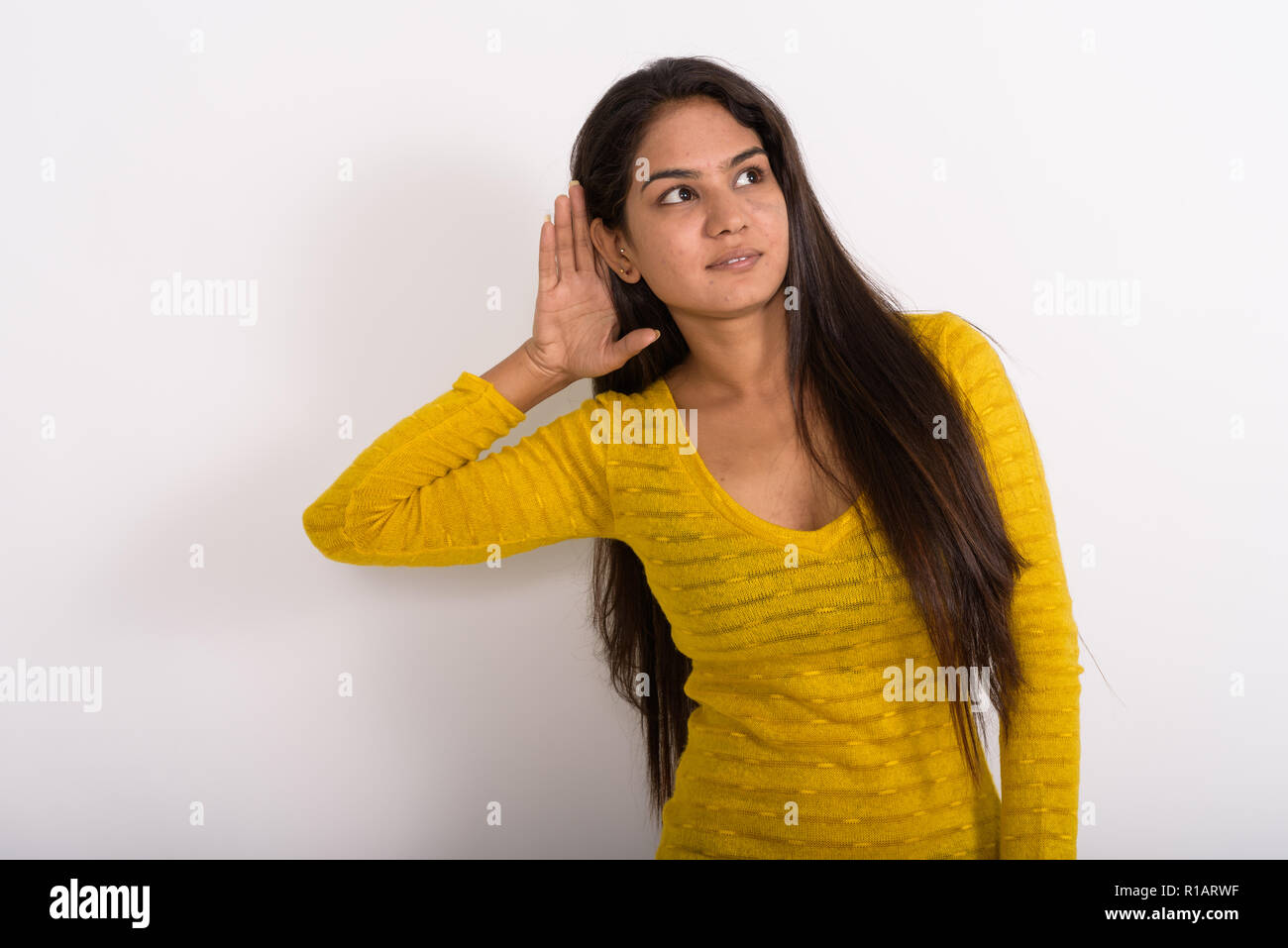 Studio shot della giovane donna indiana pensando durante l'ascolto di nuovo Foto Stock