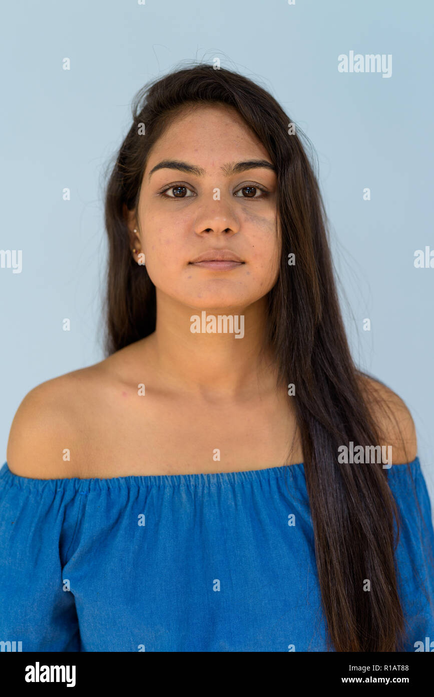 Volto di giovane donna confidentIndian contro sfondo blu Foto Stock