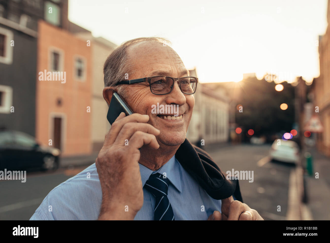 Ravvicinata di un imprenditore senior parlando su telefono cellulare. Imprenditore matura una telefonata mentre in piedi all'aperto nella strada della citta'. Foto Stock