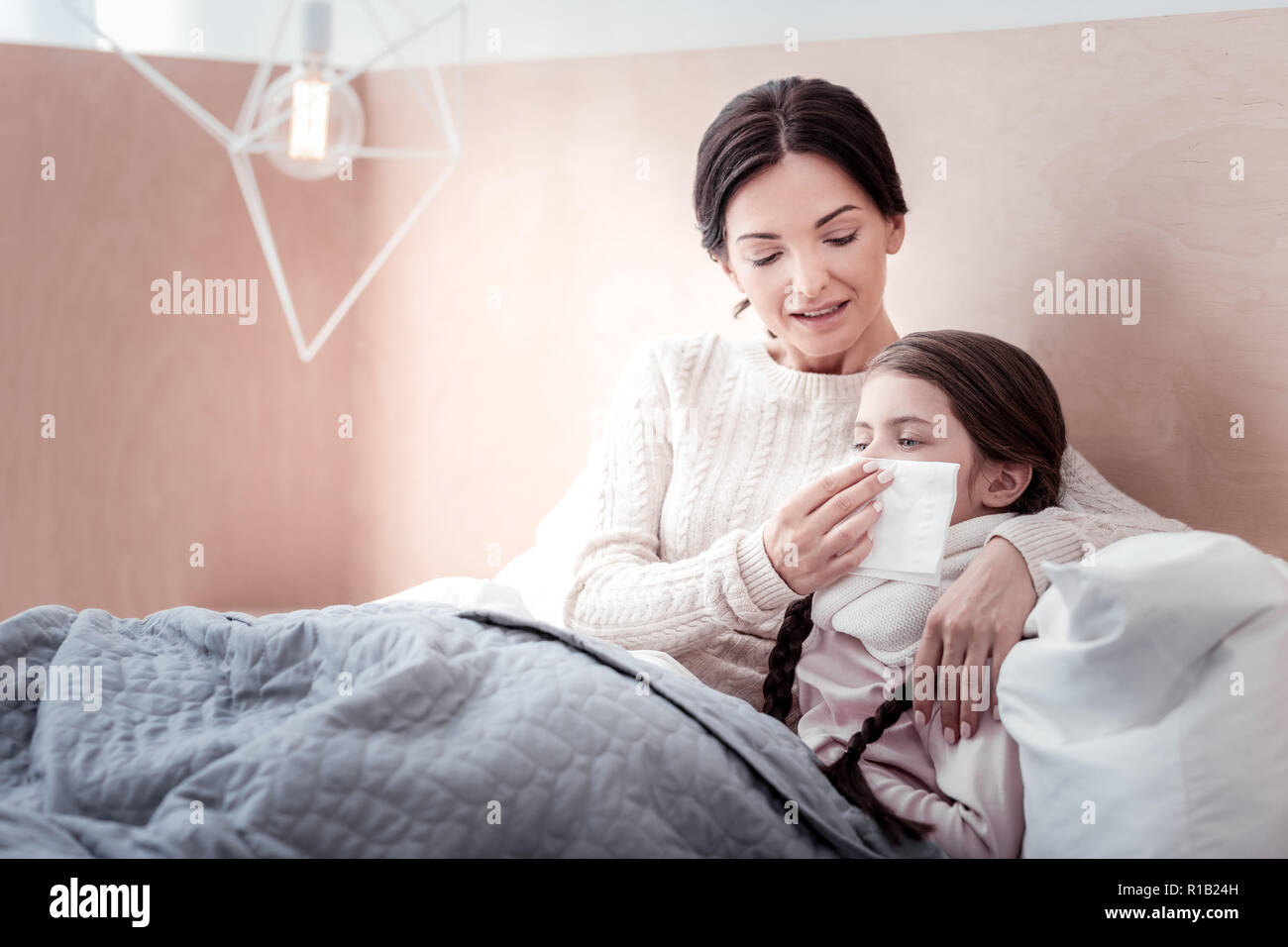 Madre attenta che giace nel letto con il suo bambino malato Foto Stock