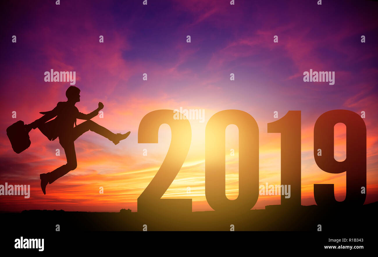 Silhouette di un giovane uomo di affari jumping al 2019 anno nuovo Foto Stock
