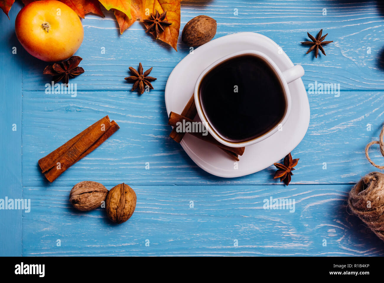 Nero caffè in una tazza bianca su un piattino con cannella noce di anice e Apple su una superficie di colore blu Foto Stock