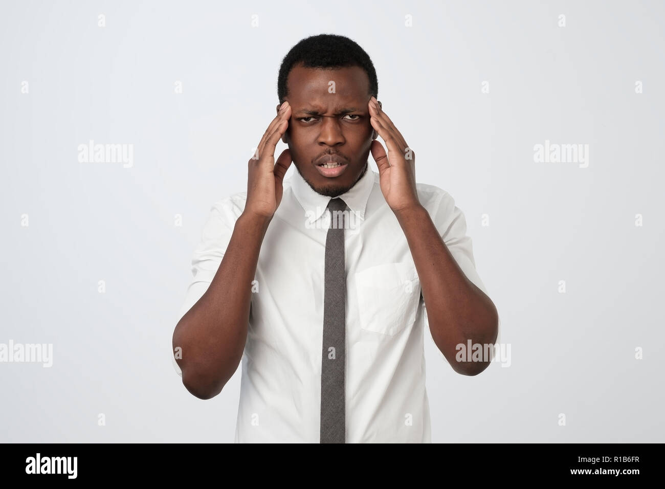 Nero Africa Uomo in camicia bianca che mostra quanto il suo mal di testa, dolore, cercando di miserabili e esaurito Foto Stock