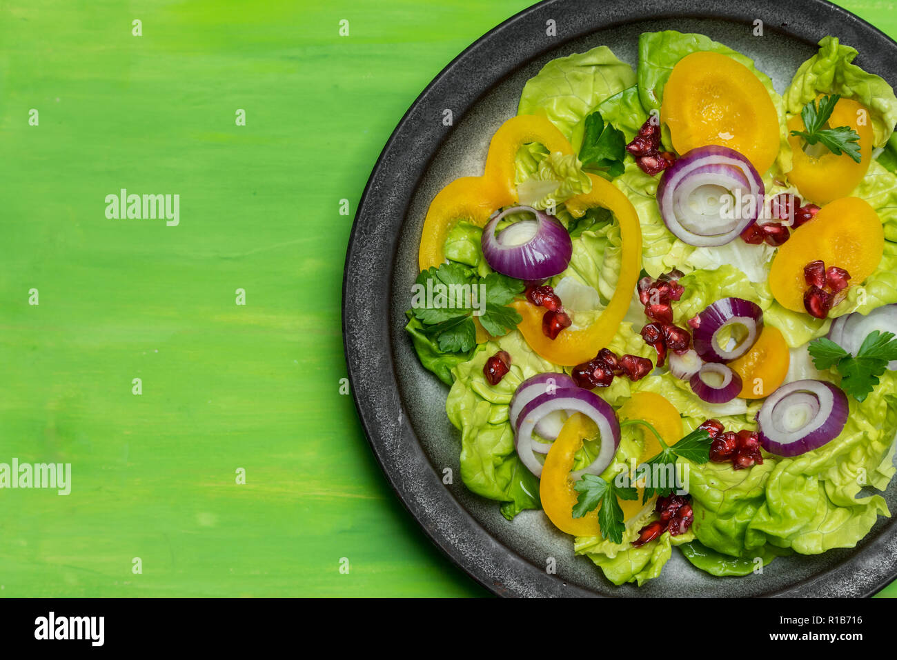 Dieta sana, insalata fresca con l'aggiunta di viola la cipolla e i semi di melograno su sfondo verde Foto Stock