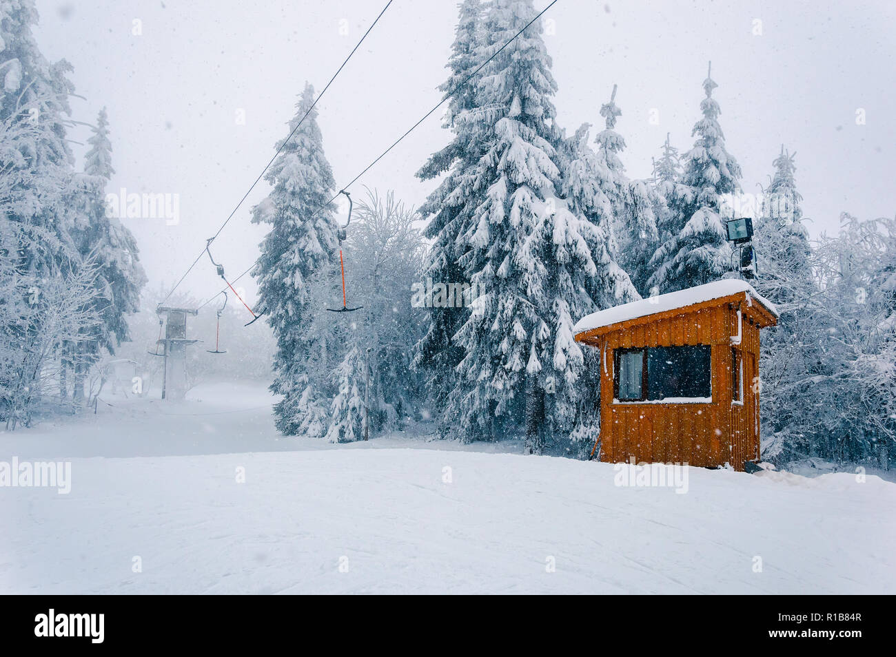 Snowy ski area: svuotare T-bar ascensore e cabine in legno a cattivo tempo invernale con neve, vento e nebbia Foto Stock