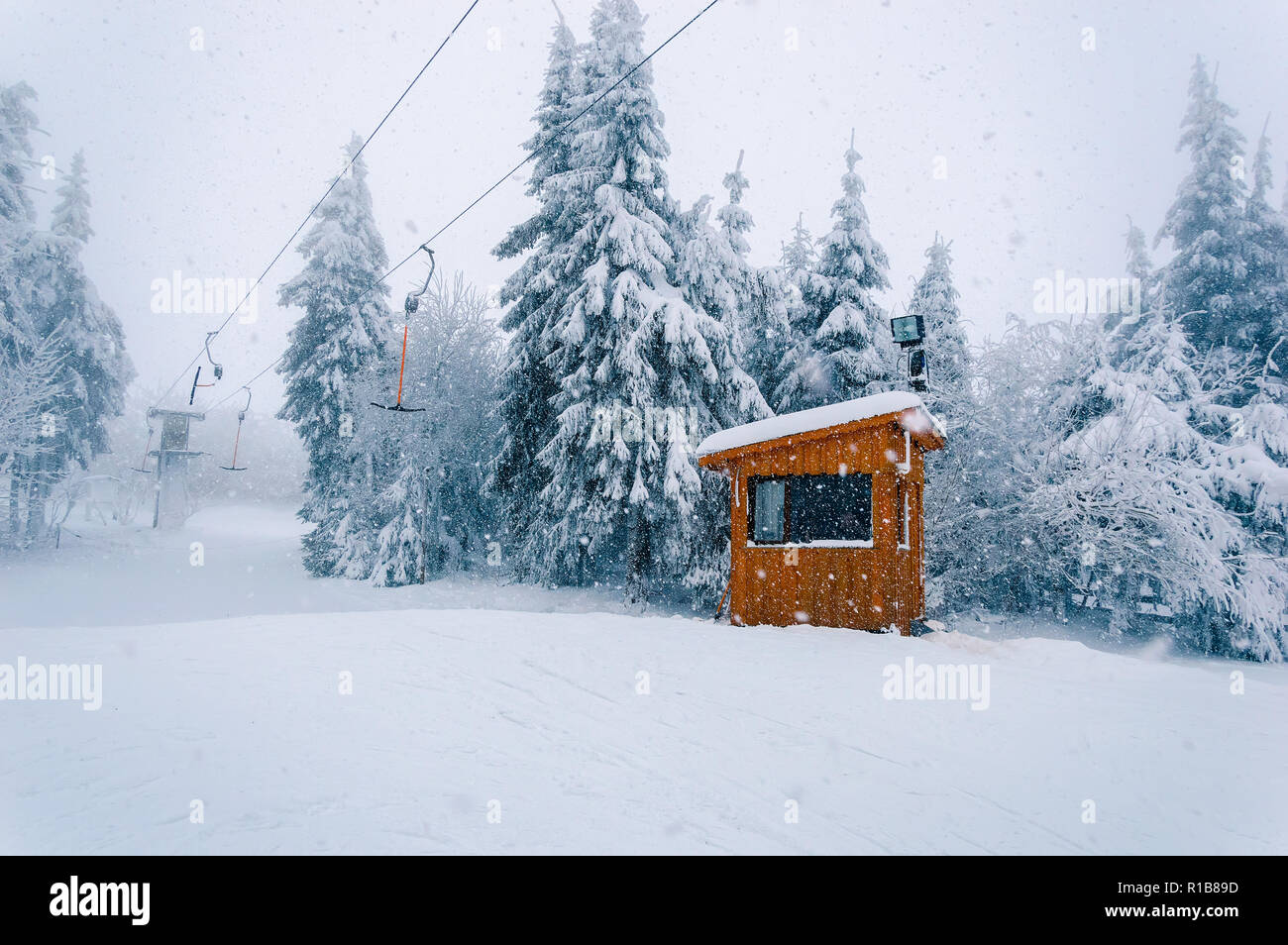 Snowy ski area: svuotare T-bar ascensore e cabine in legno a cattivo tempo invernale con neve, vento e nebbia Foto Stock