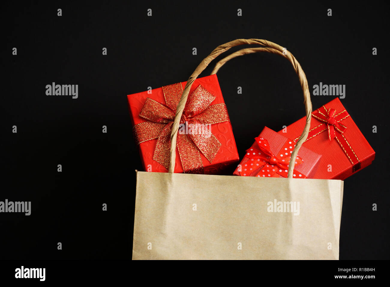 Albero confezione regalo rossa in borsa da shopping su sfondo nero per lo shopping del tema. Foto Stock