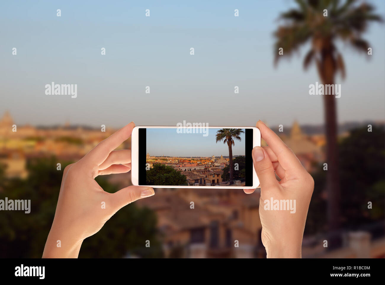 Un turista è scattare una foto della vista panoramica della mattina Roma con Palm tree in primo piano su un telefono cellulare Foto Stock