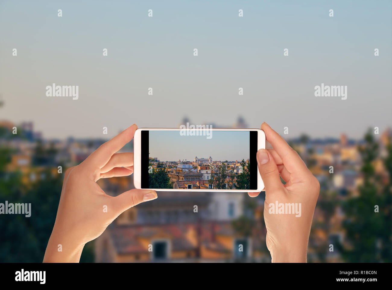 Un turista è di scattare una foto di mattina panorama di Roma con una vista del Monumento Vittoriano su un telefono cellulare Foto Stock
