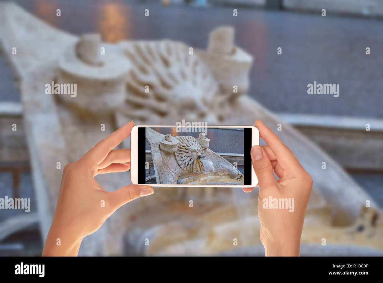 Un turista è di scattare una foto di dettaglio della fontana nella piazza di Spagna vicino alla scalinata di Piazza di Spagna a Roma su un telefono cellulare Foto Stock