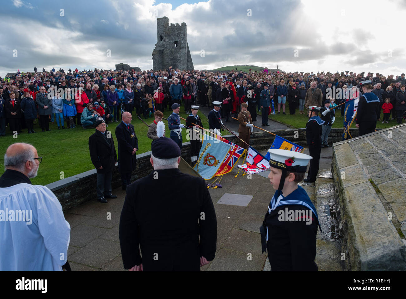 Aberystwyth Wales UK, 11/11/2018. gente radunarsi a gettare ghirlande e per ricordare i caduti di tutte le guerre e i conflitti, sul ricordo la domenica e il centesimo anniversario dell'armistizio che ha portato a termine la prima guerra mondiale, molto ventoso ma condizioni luminose all'iconico monumento ai caduti in guerra nel castello promontorio in Aberystwyth sulla costa esposta di Cardigan Bay, West Wales Photo credit Keith Morris / Alamy Live News Foto Stock