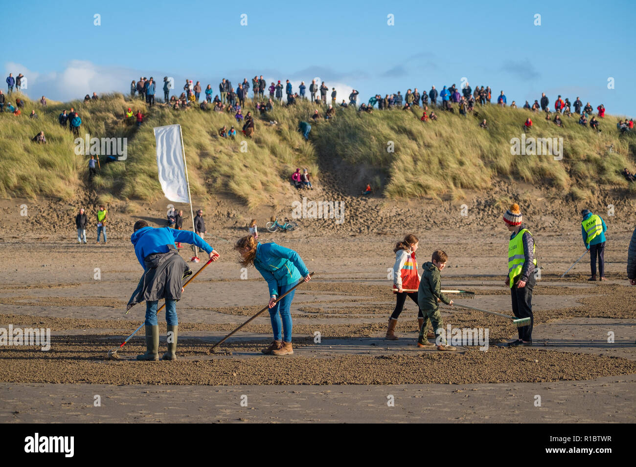 Ynyslas Wales UK, 11/11/2018. La gente guarda come un gigante 30mx30m sabbia ritratto di RICHARD DAVIES, deck mano, dal vicino villaggio di Borth, che ha servito nella Royal Navy nella prima guerra mondiale, è scolpita nella sabbia sulla spiaggia di Ynyslas , appena a nord di Aberystwyth sulla West Wales coast. Concepito dal regista Danny Boyle, questo effimero perforato del memorial arte - Pagine di mare - è uno dei 28 creato su spiagge in tutto il Regno Unito in questo giorno, ricordo la domenica, il centesimo anniversario dell'armistizio che ha portato a termine la prima guerra mondiale Photo credit Keith Morris / Alamy Live News Foto Stock