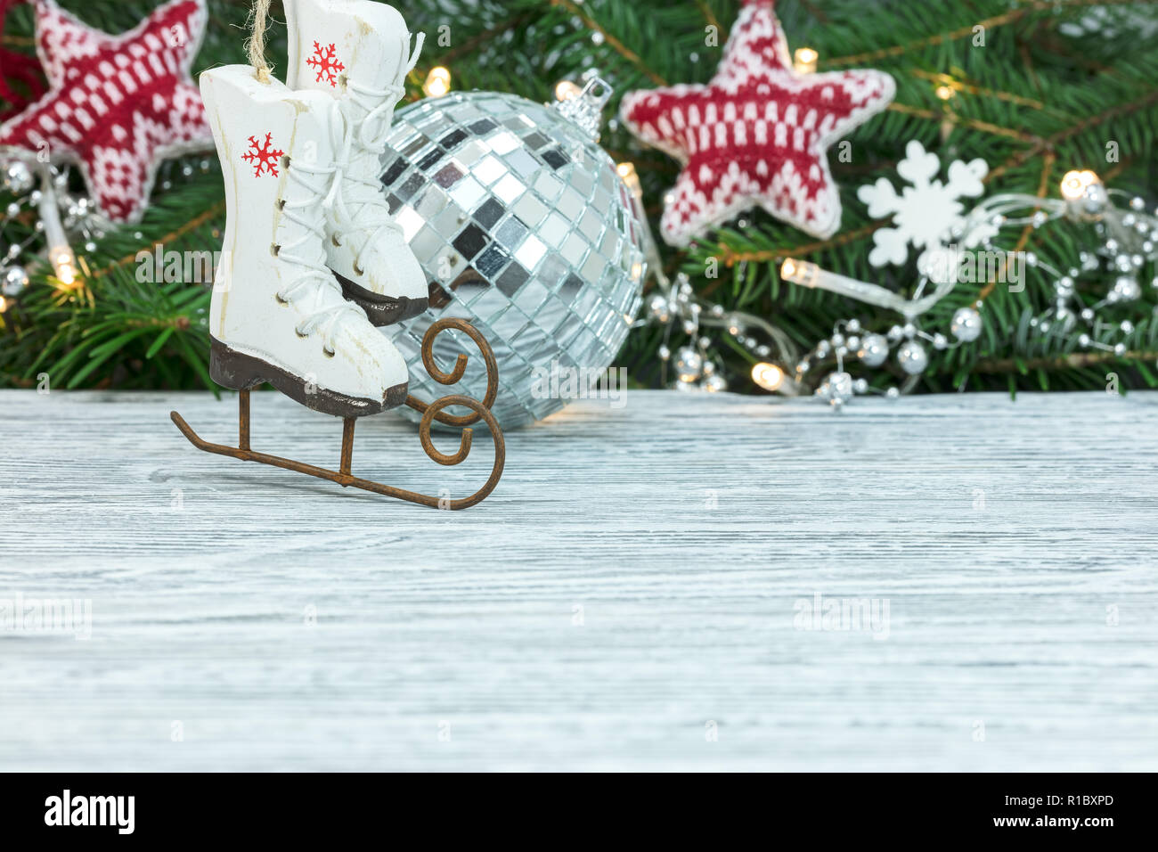Albero di natale ramo decorato con luci. piccoli pattini decorativo, argento Palla di vetro e stelle su bianco tavolo in legno Foto Stock