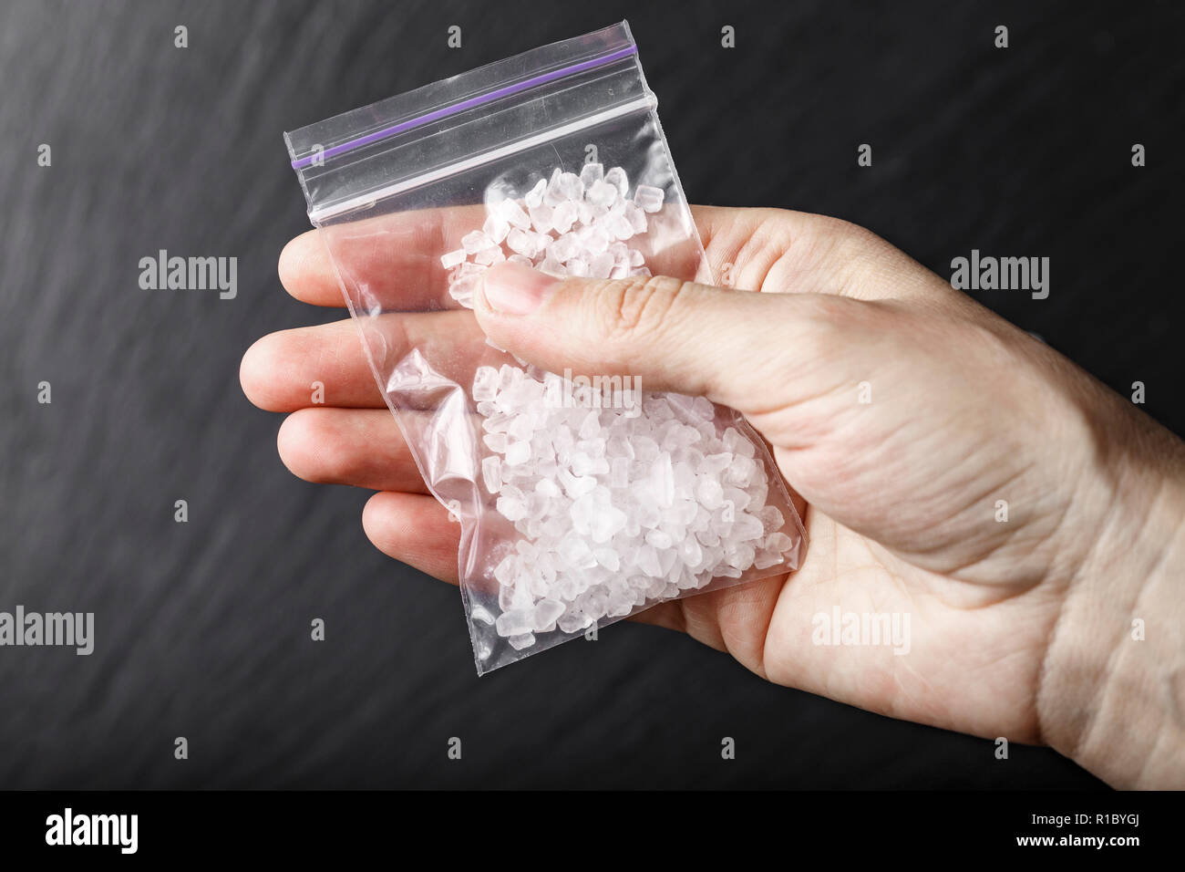 Un sacco di farmaci in forma di cristalli bianchi in mano Foto Stock