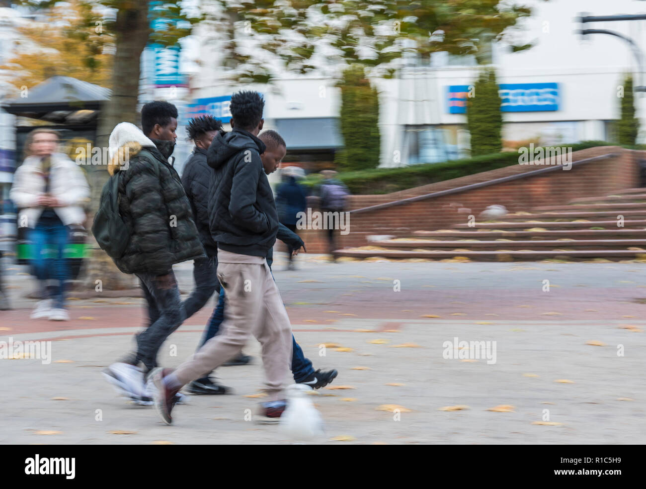 Piccolo gruppo di giovani uomini neri nel loro 20's camminando in una frenetica città dello shopping in Worthing West Sussex, in Inghilterra, Regno Unito. Foto Stock