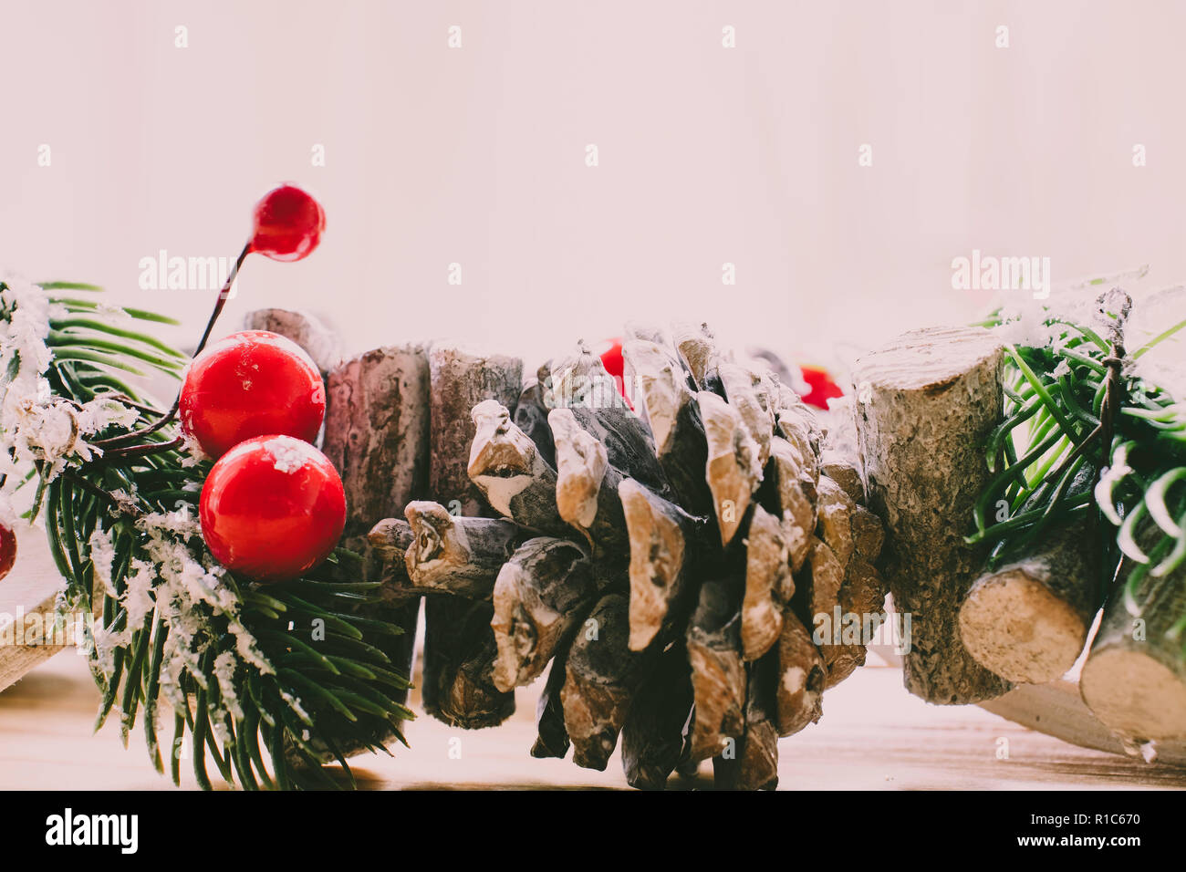 Scandinavian ghirlanda di Natale con bacche rosse e pigne sulla luce di un tavolo di legno Foto Stock