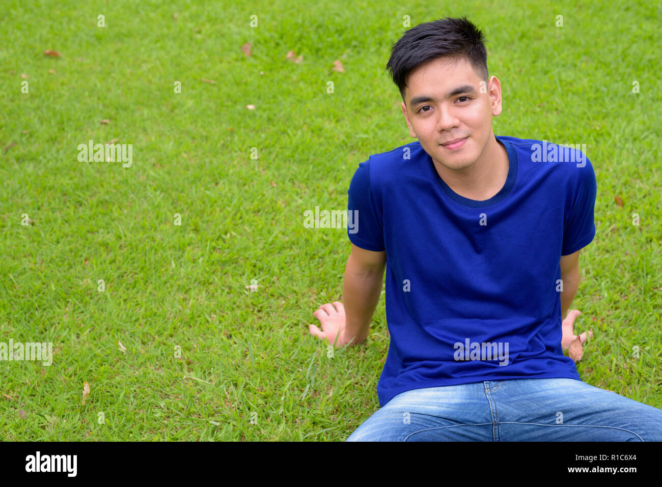Bel giovane uomo asiatico di relax presso il parco Foto Stock