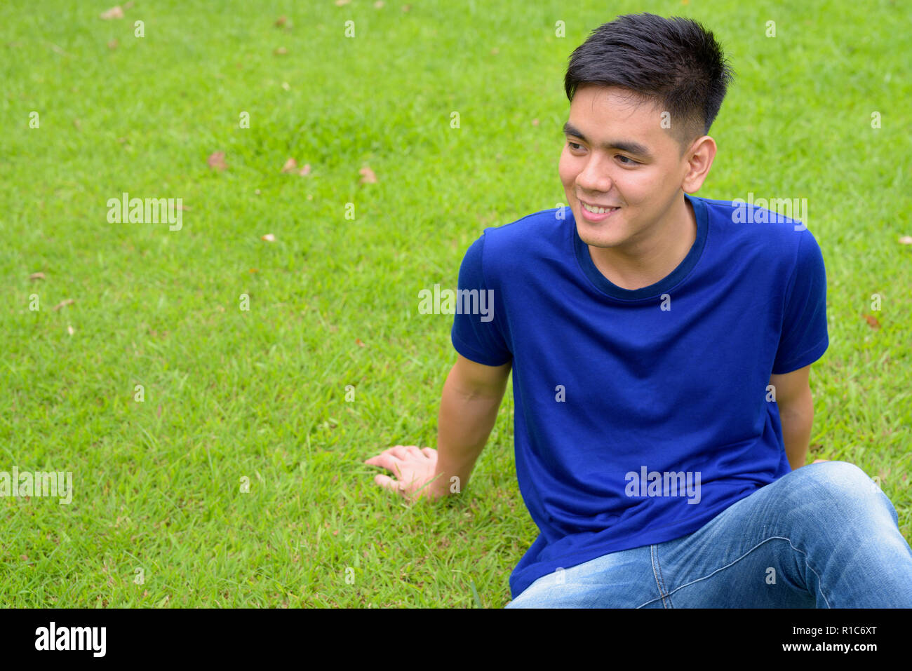 Bel giovane uomo asiatico di relax presso il parco Foto Stock