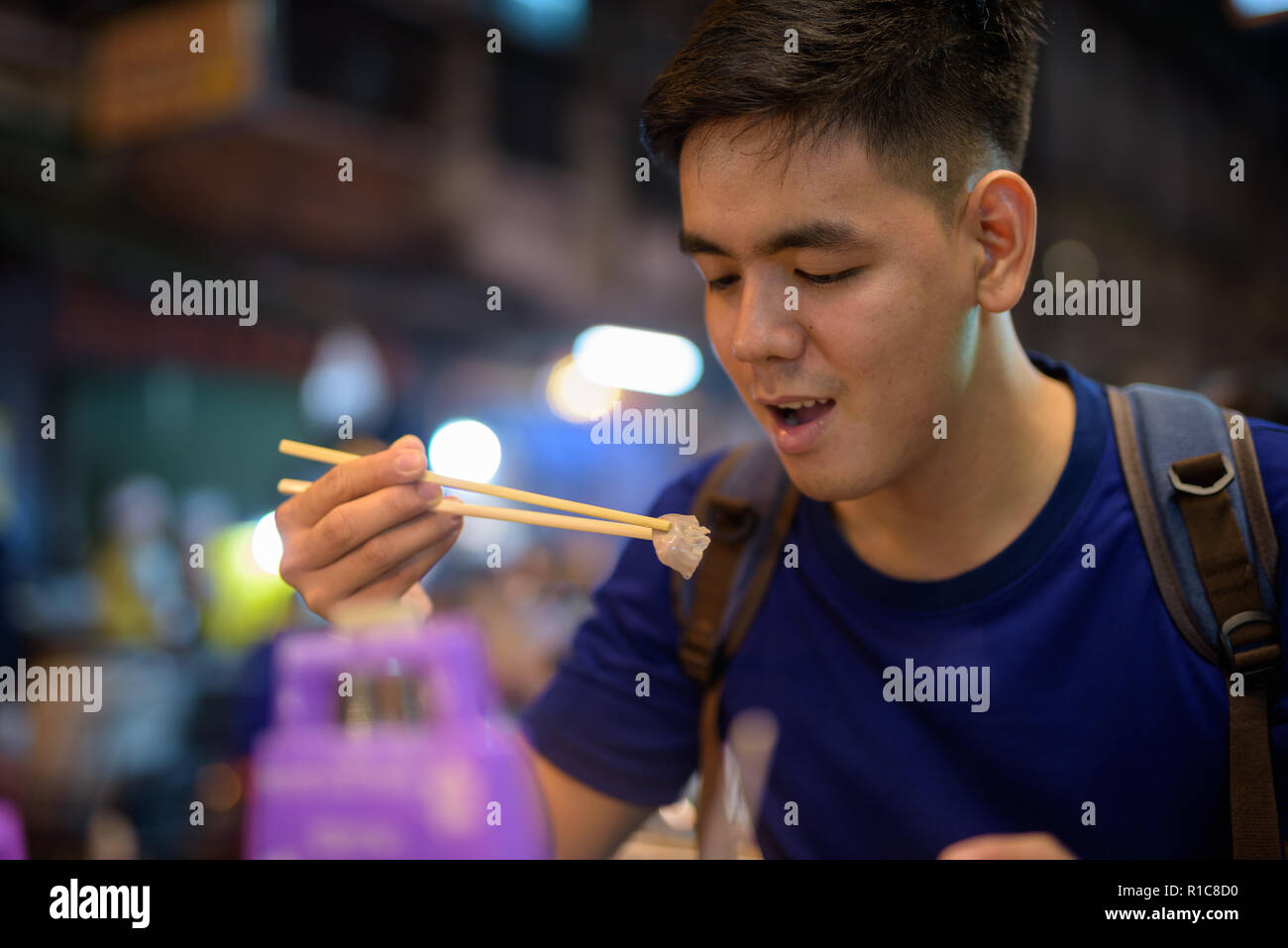 Giovani asiatici uomo turistico esplorare a Chinatown mentre mangia una zuppa di noodle al Foto Stock