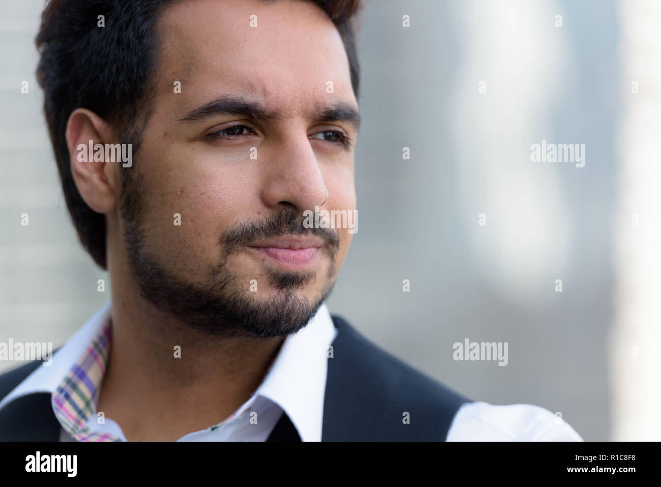 Ravvicinata di un bel giovane uomo indiano pensando all'aperto in c Foto Stock