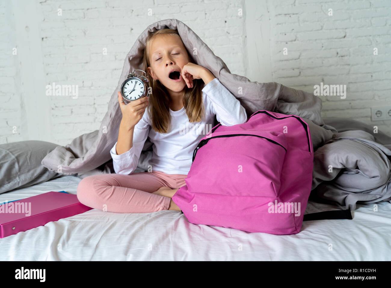 Bella bionda bambina triste e insonni arrabbiato che mostra orologio sveglia  tempo di prepararsi per la scuola in difficoltà di svegliarvi al mattino  bambini Foto stock - Alamy