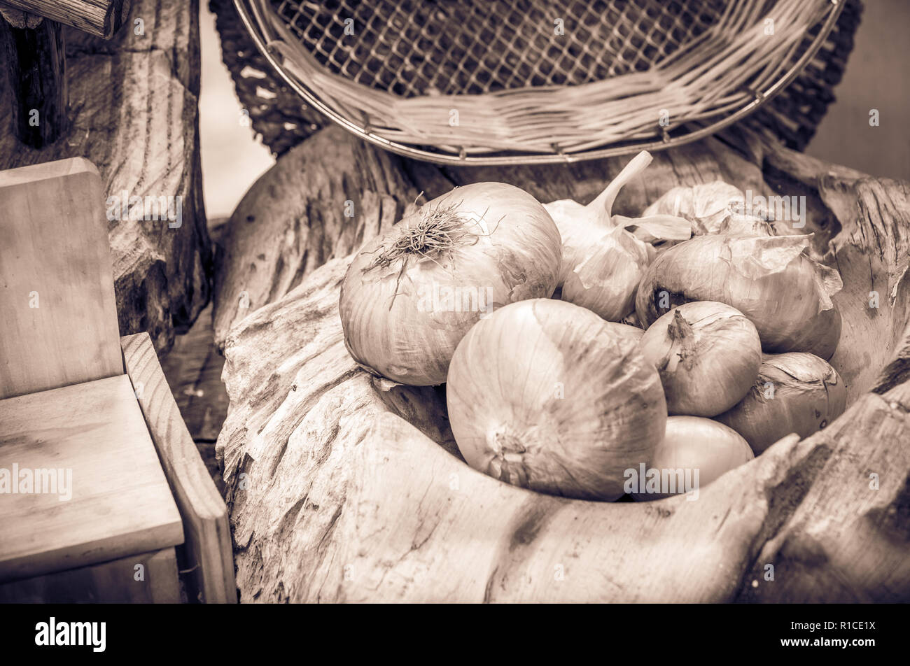 Tonalità seppia rustico vita ancora, cipolle e utensili da cucina in legno Foto Stock