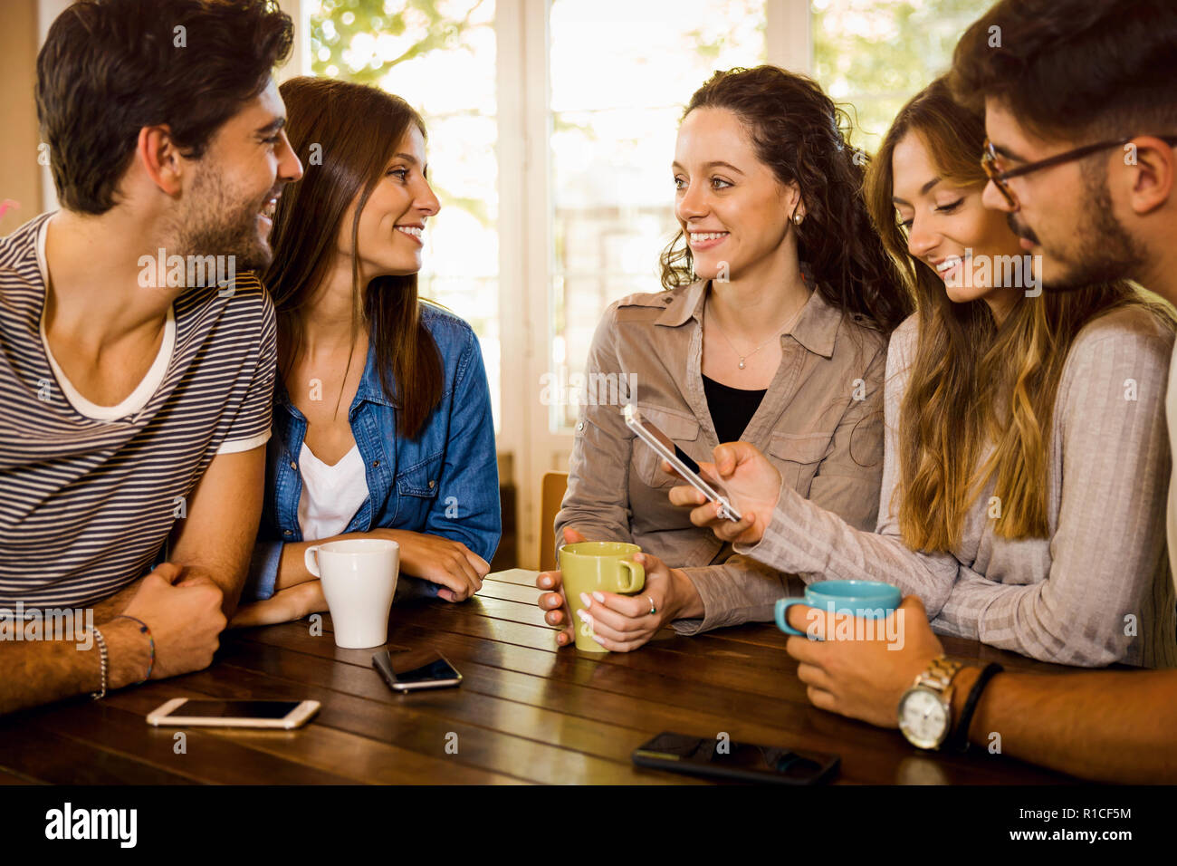 Un gruppo di amici a parlare e a bere caffè presso la caffetteria Foto Stock