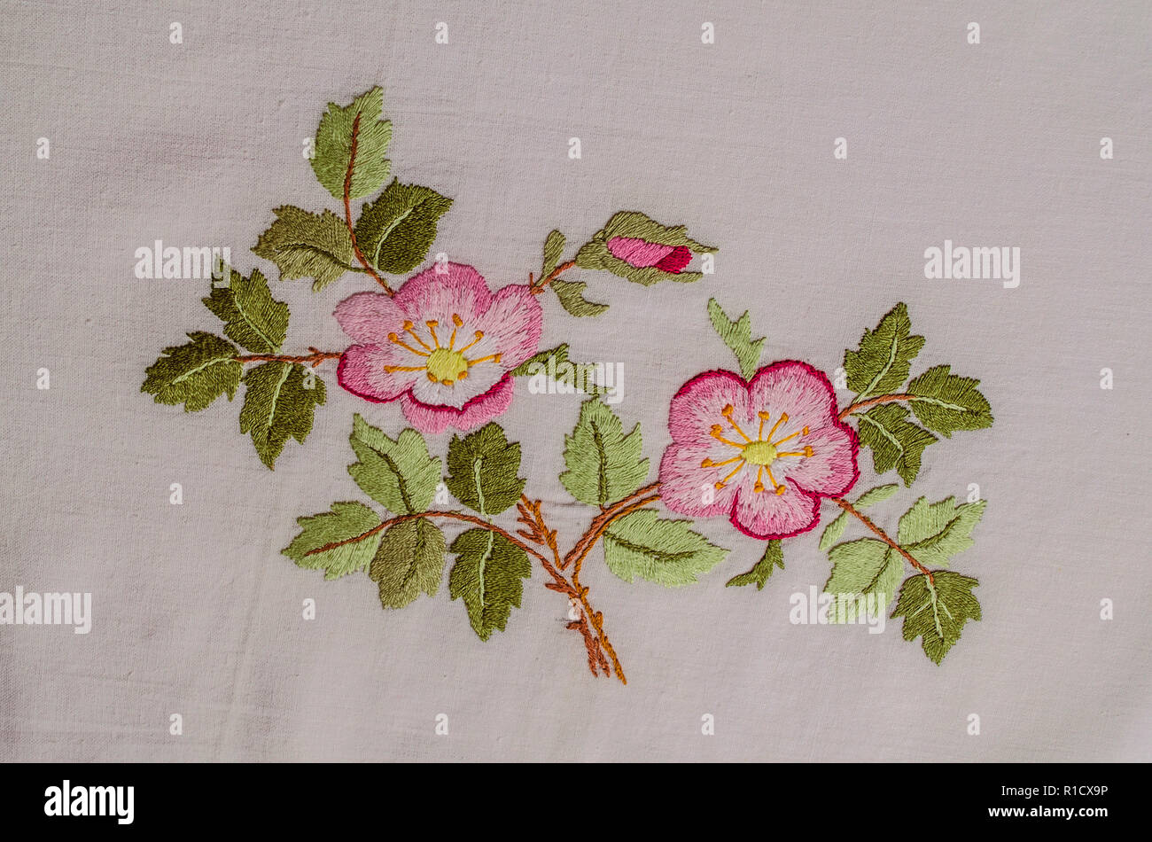 Yerevan, Armenia, 04,Giugno,2018: rametto con fiori di colore rosa tea rose con una gemma e foglie, ricamato un satin stitch sulla ruvida stoffa di cotone Foto Stock