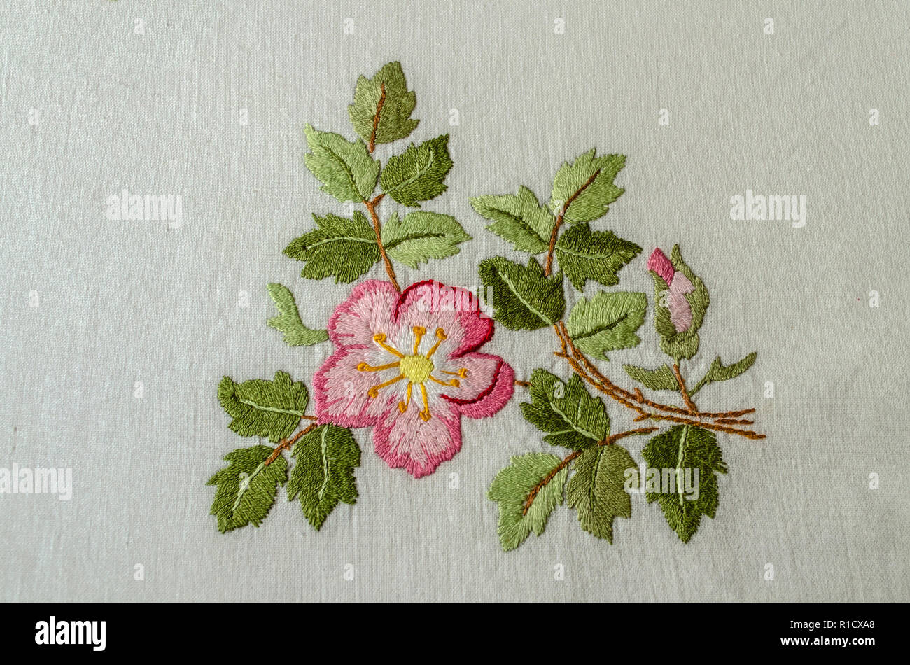 Yerevan, Armenia, 04,Giugno,2018: fiori di colore rosa tea rose con una gemma e foglie,ricamato un satin stitch sulla ruvida stoffa di cotone Foto Stock