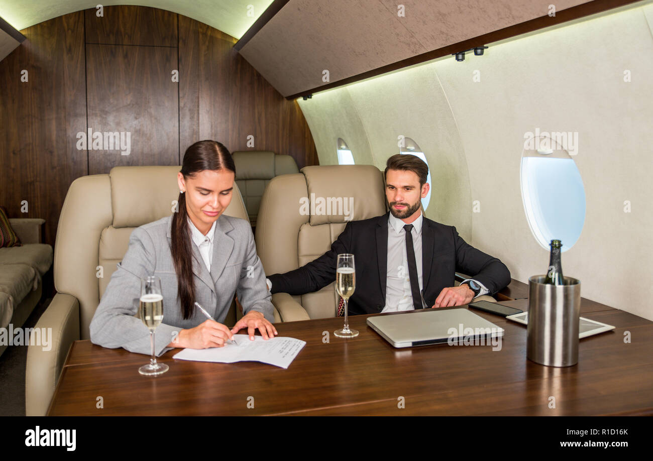 Imprenditore e la donna a lavorare mentre viaggia su un jet privato - Ritratto di gente di affari tenendo una prima classe per il volo per lavorare, concetti su busin Foto Stock