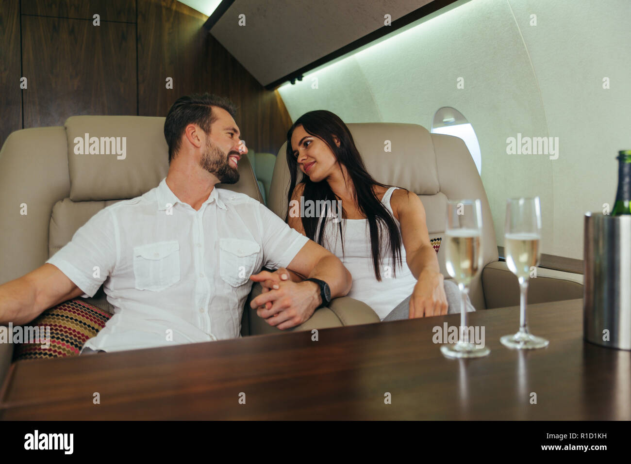 Coppia felice che viaggiano su un lusso jet privato - i giovani adulti viaggiano su un primo volo di classe, concetti sui viaggi e stile di vita Foto Stock