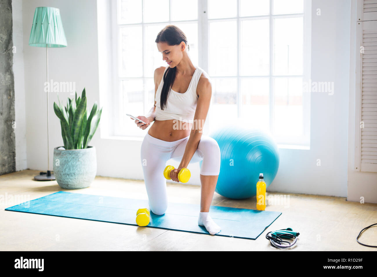 Ahtletic bella donna training at home - Giovane ragazza fitness facendo nel suo appartamento, concetti sul fitness, sport e salute Foto Stock