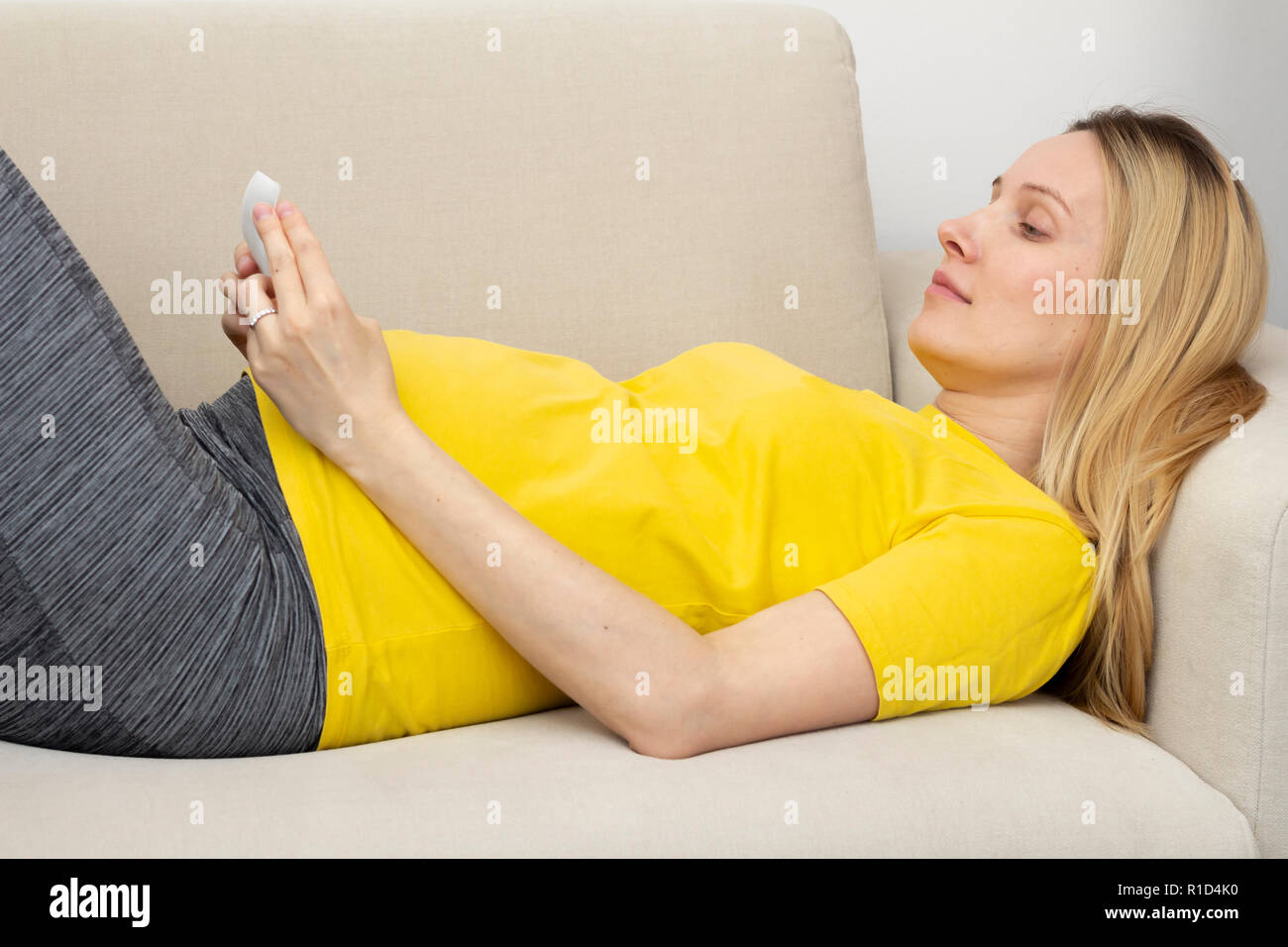 Donna incinta sdraiato sul divano Foto Stock