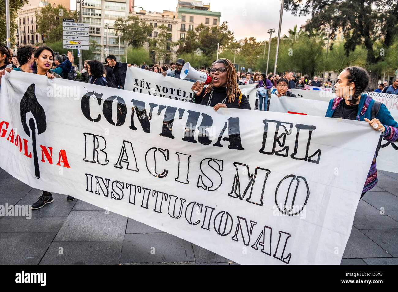 Una donna con un megafono è visto dietro un banner durante la dimostrazione. Una nuova manifestazione contro il razzismo istituzionale ha attraversato le strade del centro di Barcellona. Accompagnata da organizzazioni sociali e il Sindacato dei venditori ambulanti, più di 500 persone hanno rivendicato per terminare il razzismo a Barcellona e hanno denunciato le identificazioni di polizia secondo il colore della loro pelle. Foto Stock