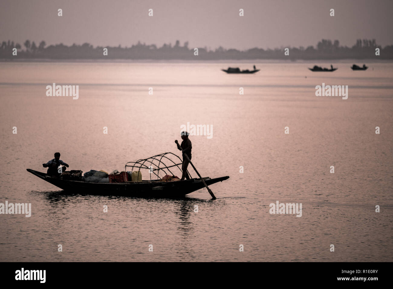 I pescatori e barche stagliano contro la luce della sera nel Subarbans, West Bengal, India Foto Stock