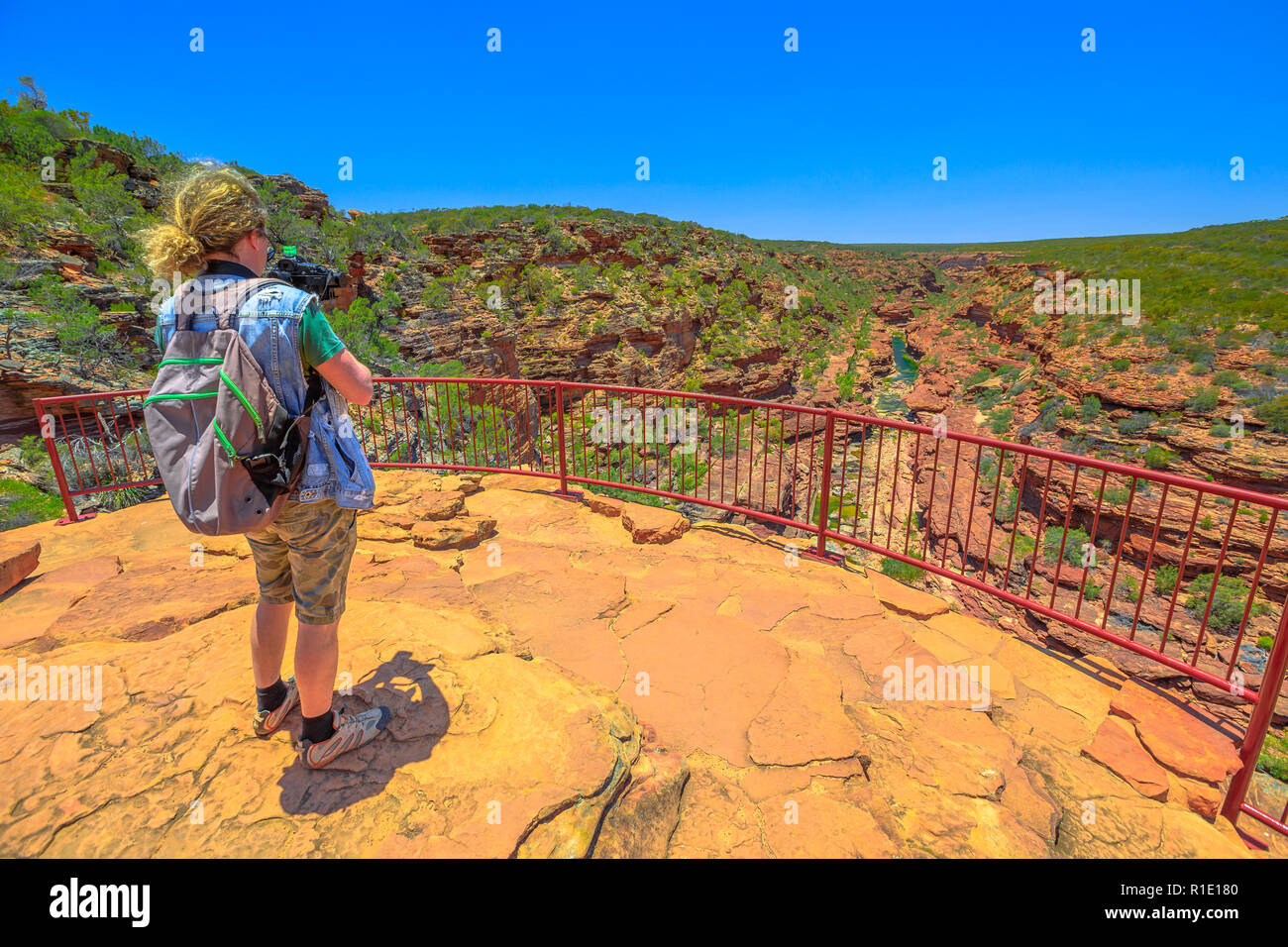 Fotografo di viaggio zaino in spalla con lo stabilizzatore ha girato a Z-Bend lookout in Kalbarri National Park, Australia occidentale. Videomaker professionale con fotocamera scatta foto in outback australiano. Foto Stock