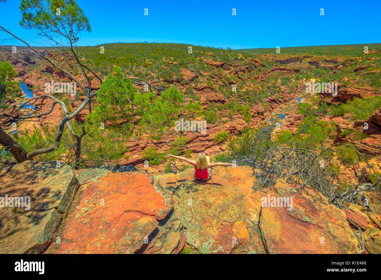 Felice donna bionda godendo a Z-Bend lookout al fiume Murchison in Kalbarri National Park, Australia occidentale. Libertà caucasian traveler in entroterra australiano. Cielo blu, durante la stagione estiva. Copia dello spazio. Foto Stock