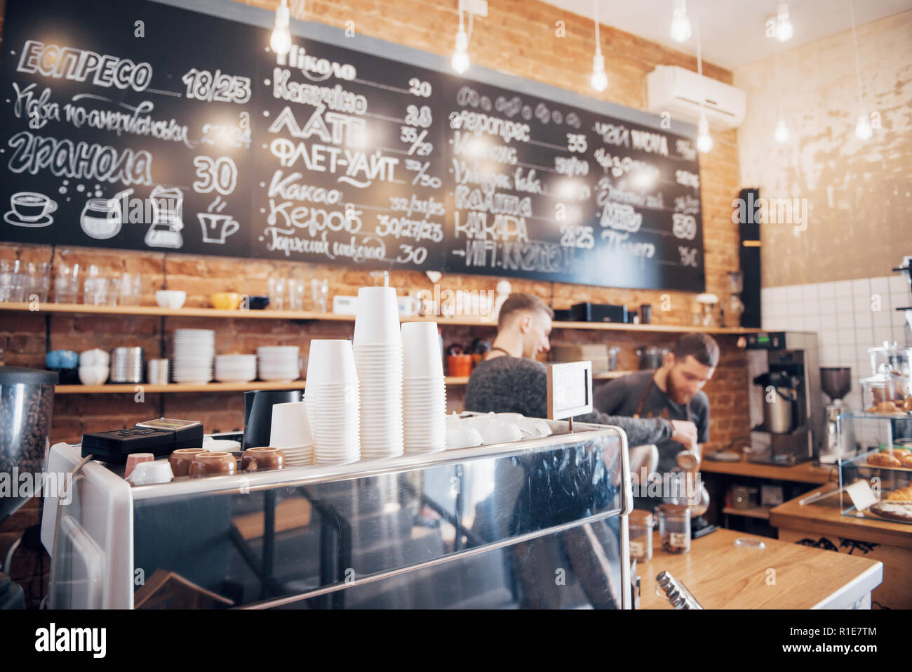 Hipster cercando coffee shop pronto per aprire la giornata con un pulito e ordinato il contatore e ben mantenuto lucido macchina da caffè sulla superficie di legno Foto Stock