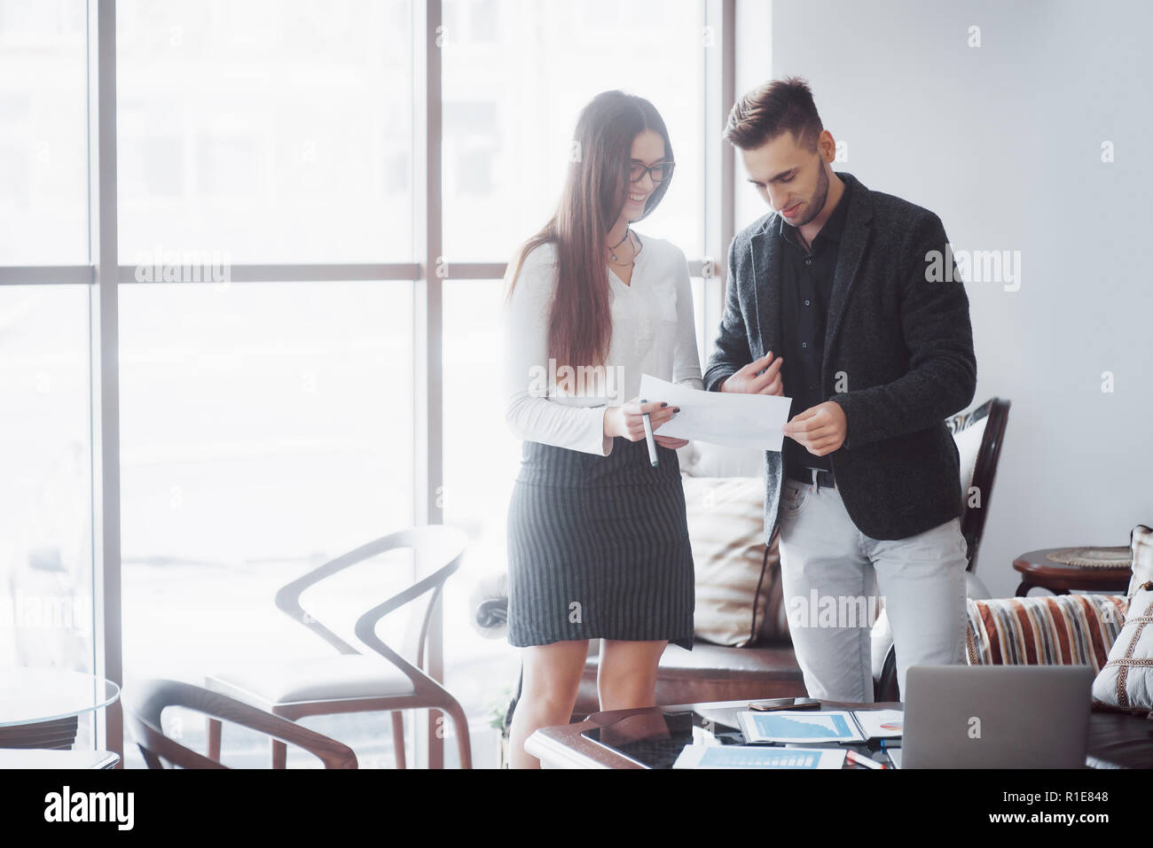 Imprenditore e business donna studiare un grafico sulla piastra e documenti cartacei in corrispondenza della finestra sullo sfondo della città di office in un piano alto Foto Stock