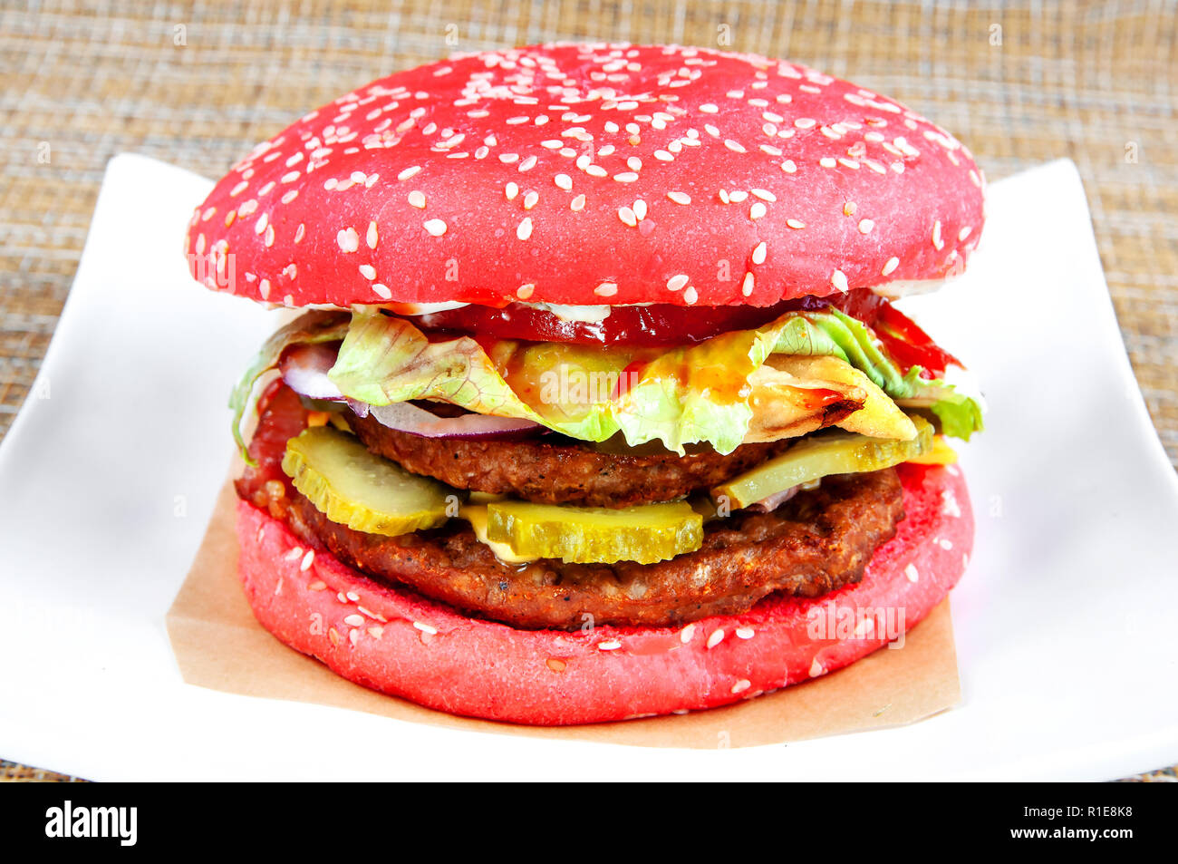 Hamburger classico rosso con pane e verdure fresche su una piastra bianca.  Sfondo bianco Foto stock - Alamy
