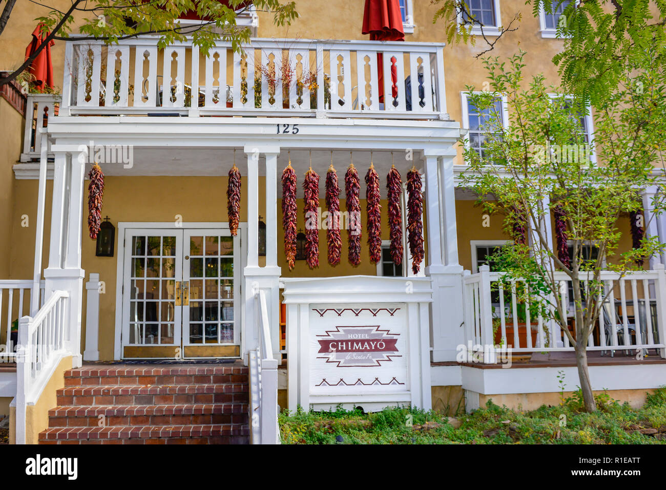 Peperoncino rosso ristras appendere dal portico del boutique Hotel Chimayo di Santa Fe, ricco di storia e di cultura nel centro storico di Santa Fe, NM, Stati Uniti d'America Foto Stock