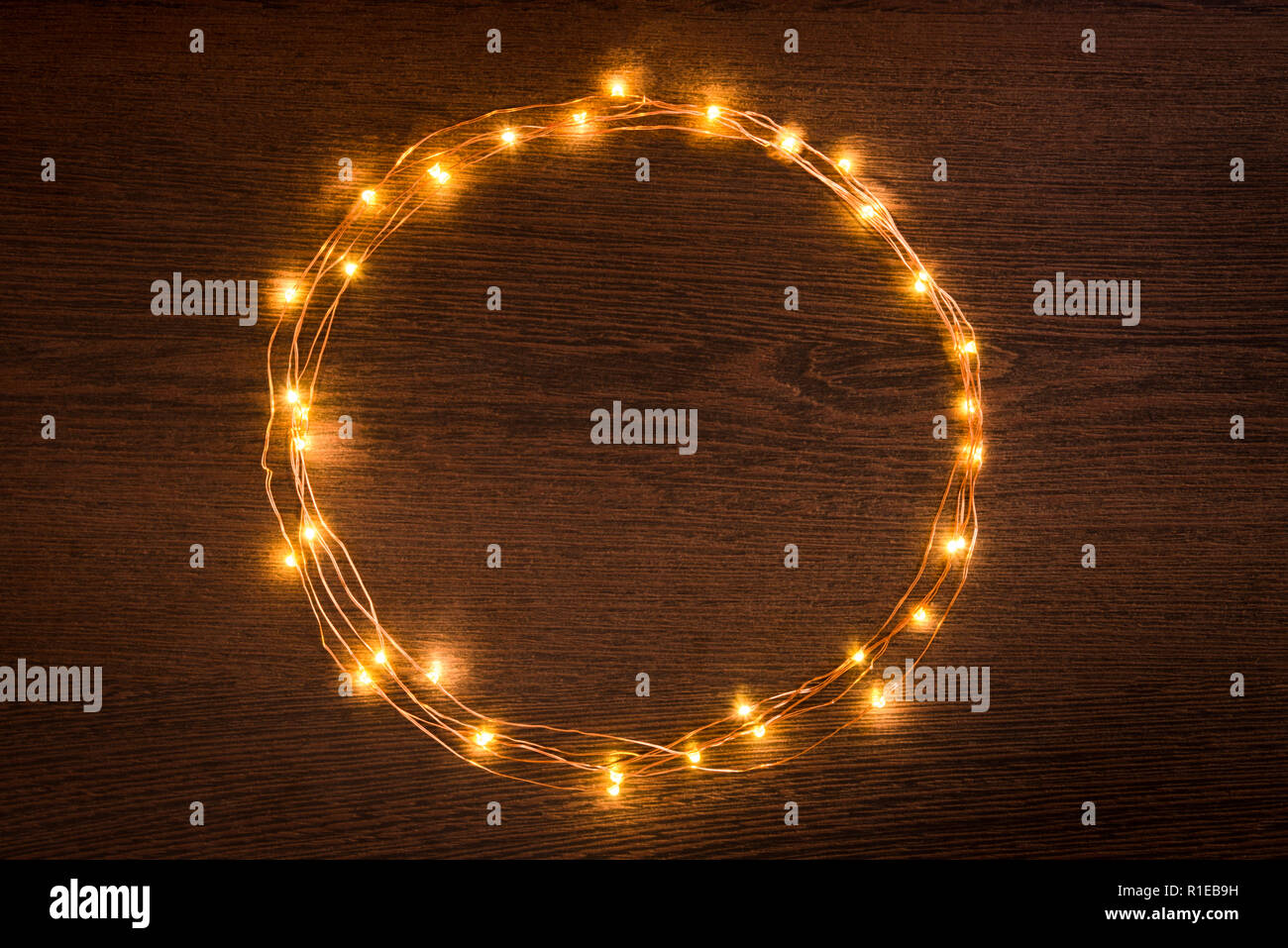 Le luci di Natale ghirlanda bordo circolare su legno scuro dello sfondo. Laici piana, copia dello spazio. Foto Stock