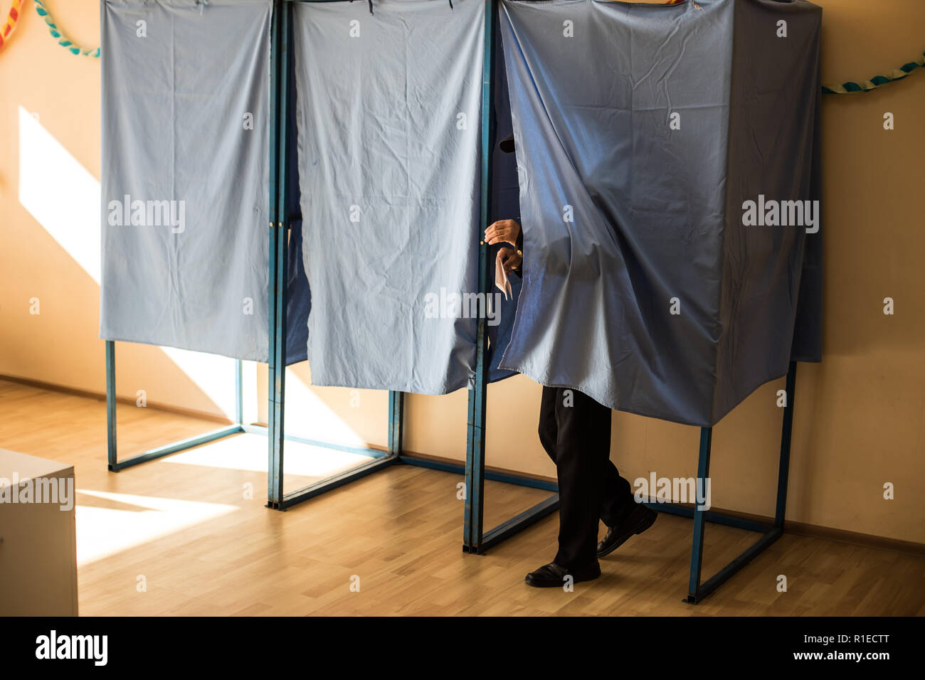 Immagine a colori di una persona non identificabili voto in capanne in corrispondenza di una stazione di polling, durante le elezioni. Foto Stock