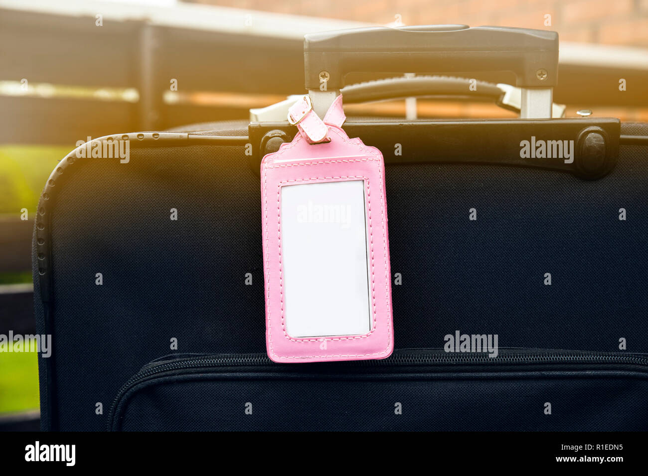 Femminile rosa bagagli vuoti targhetta fissata al bagaglio nero valigia. Perso, trovato elemento di design concept. Foto Stock